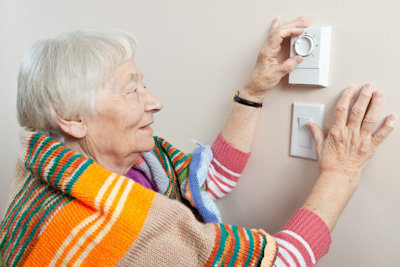 Senior woman adjusting her thermostat